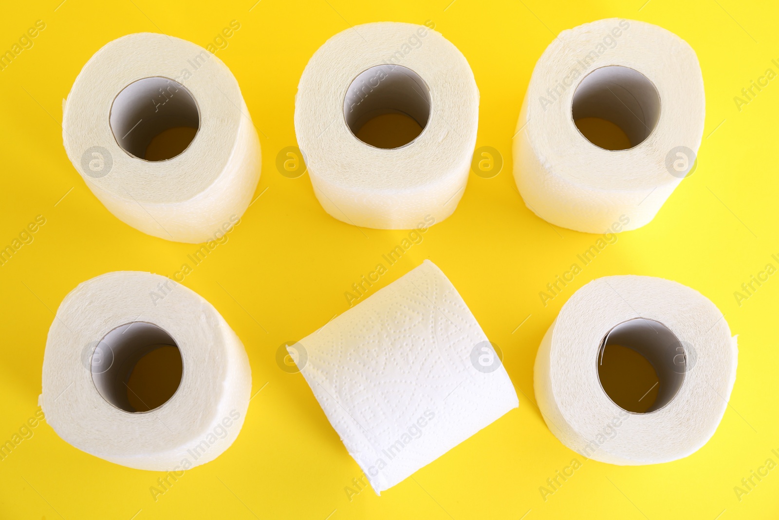 Photo of Many soft toilet paper rolls on yellow background, flat lay