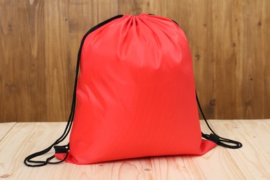 Red drawstring bag on light wooden table