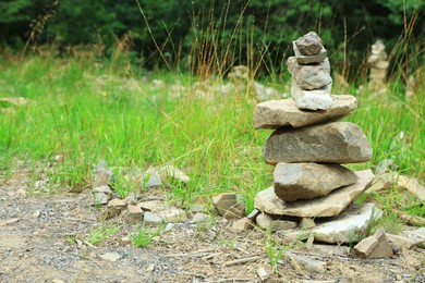 Many stacked stones on green grass outdoors, space for text