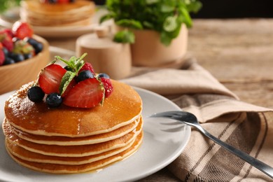 Tasty pancakes with fresh berries and mint on wooden table, closeup. Space for text