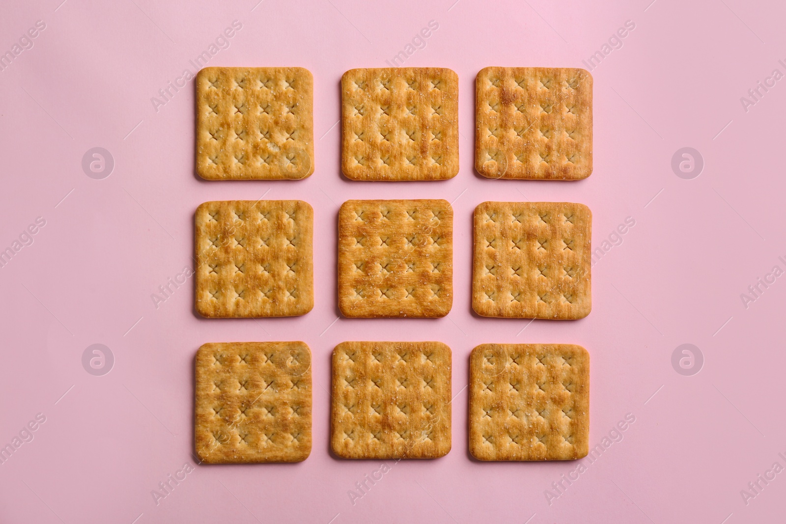 Photo of Delicious crackers on pink background, flat lay