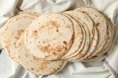 Photo of Tasty homemade tortillas and cloth on table, top view
