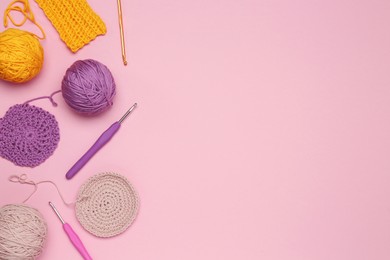 Photo of Flat lay composition with knitting threads and crochet hooks on pink background, space for text