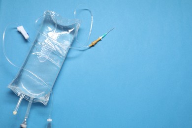 Photo of IV infusion set on light blue background, top view. Space for text