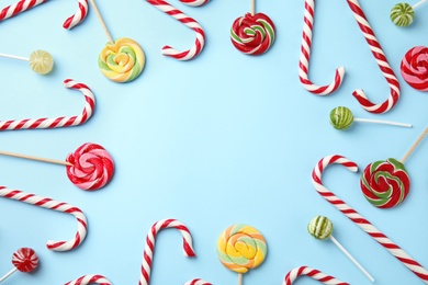 Photo of Flat lay composition with candy canes and lollipops on light blue background. Space for text