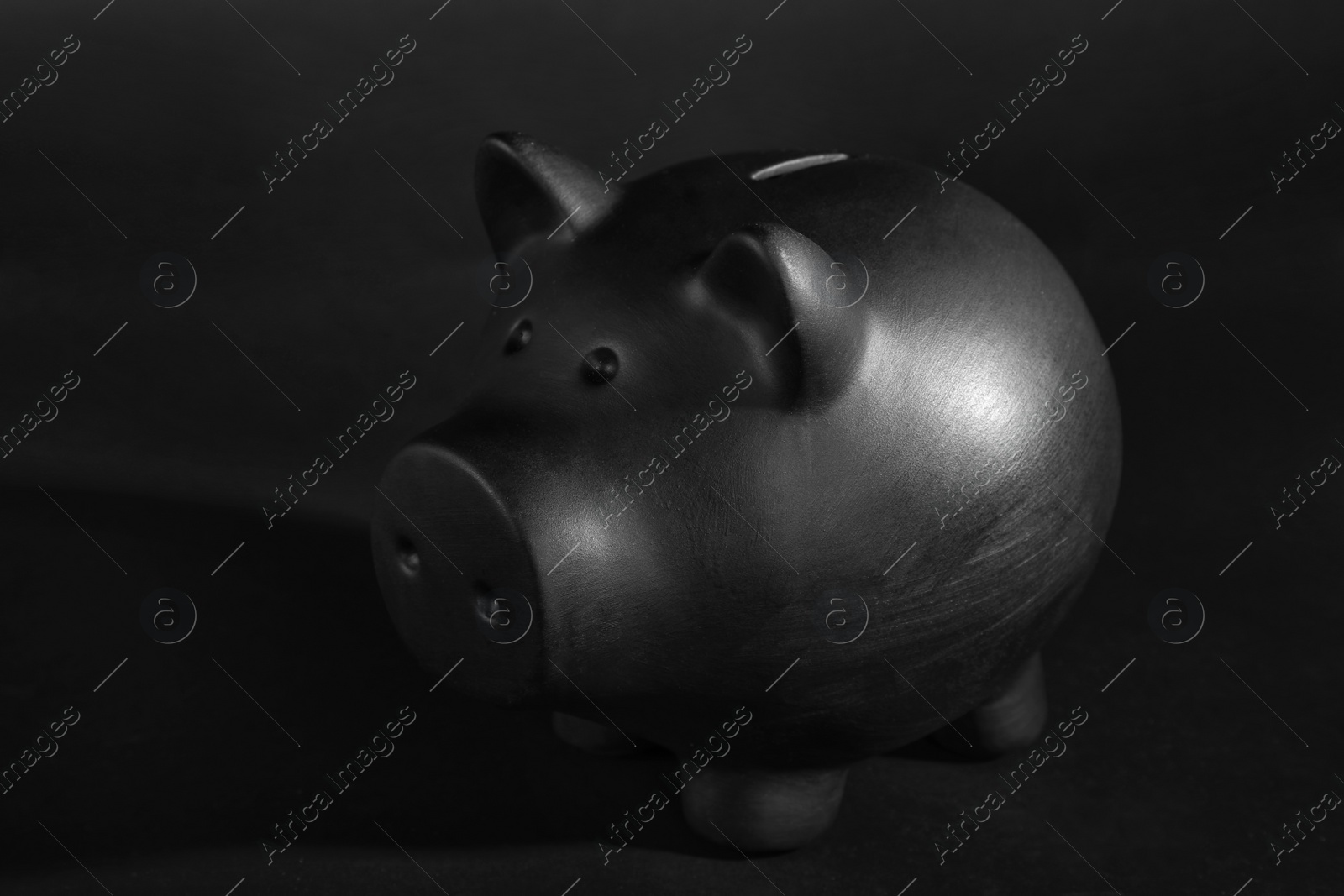 Photo of Black piggy bank on table against dark background