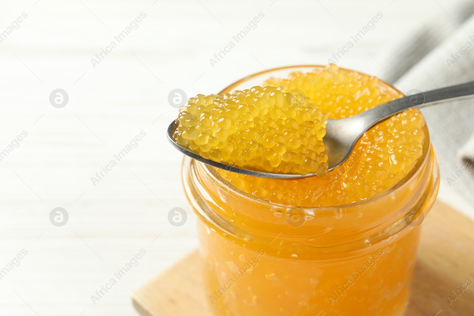 Photo of Taking fresh pike caviar from glass jar on white table, closeup. Space for text