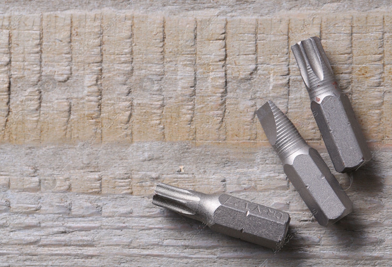 Photo of Different screwdriver bits on wooden table, top view. Space for text