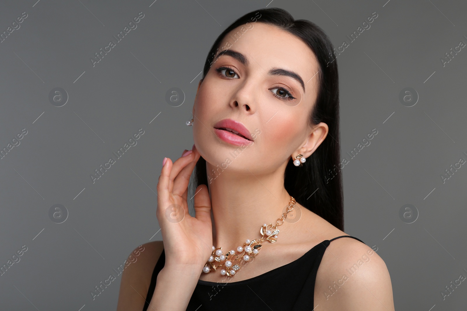 Photo of Beautiful young woman with elegant jewelry on dark grey background