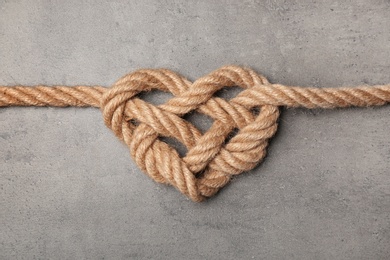 Heart made of rope on grey background, top view