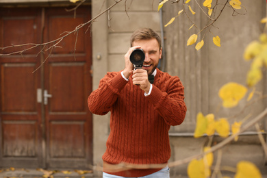 Photo of Young man using vintage video camera outdoors