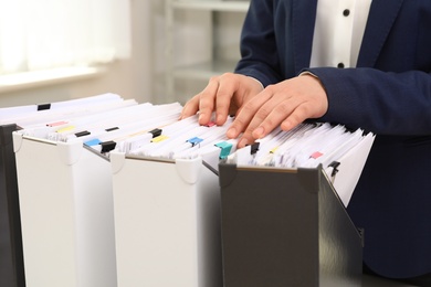 Woman taking documents from folder in archive, closeup