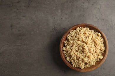 Cooked delicious quinoa in wooden bowl on table, top view. Space for text