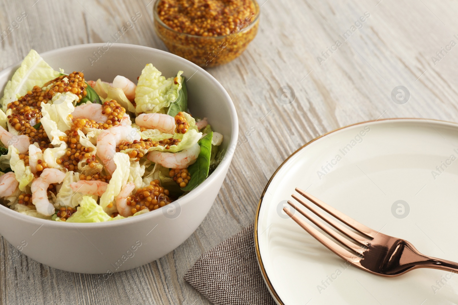 Photo of Delicious salad with Chinese cabbage, shrimps and mustard seed dressing served on white wooden table