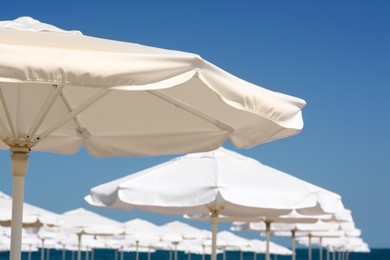 Beautiful white beach umbrellas against blue sky, closeup