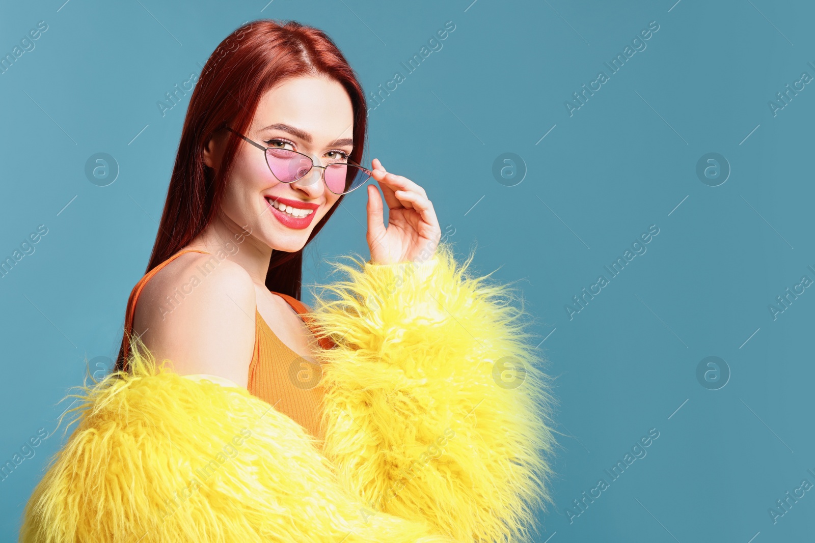 Photo of Stylish woman with red dyed hair on light blue background, space for text