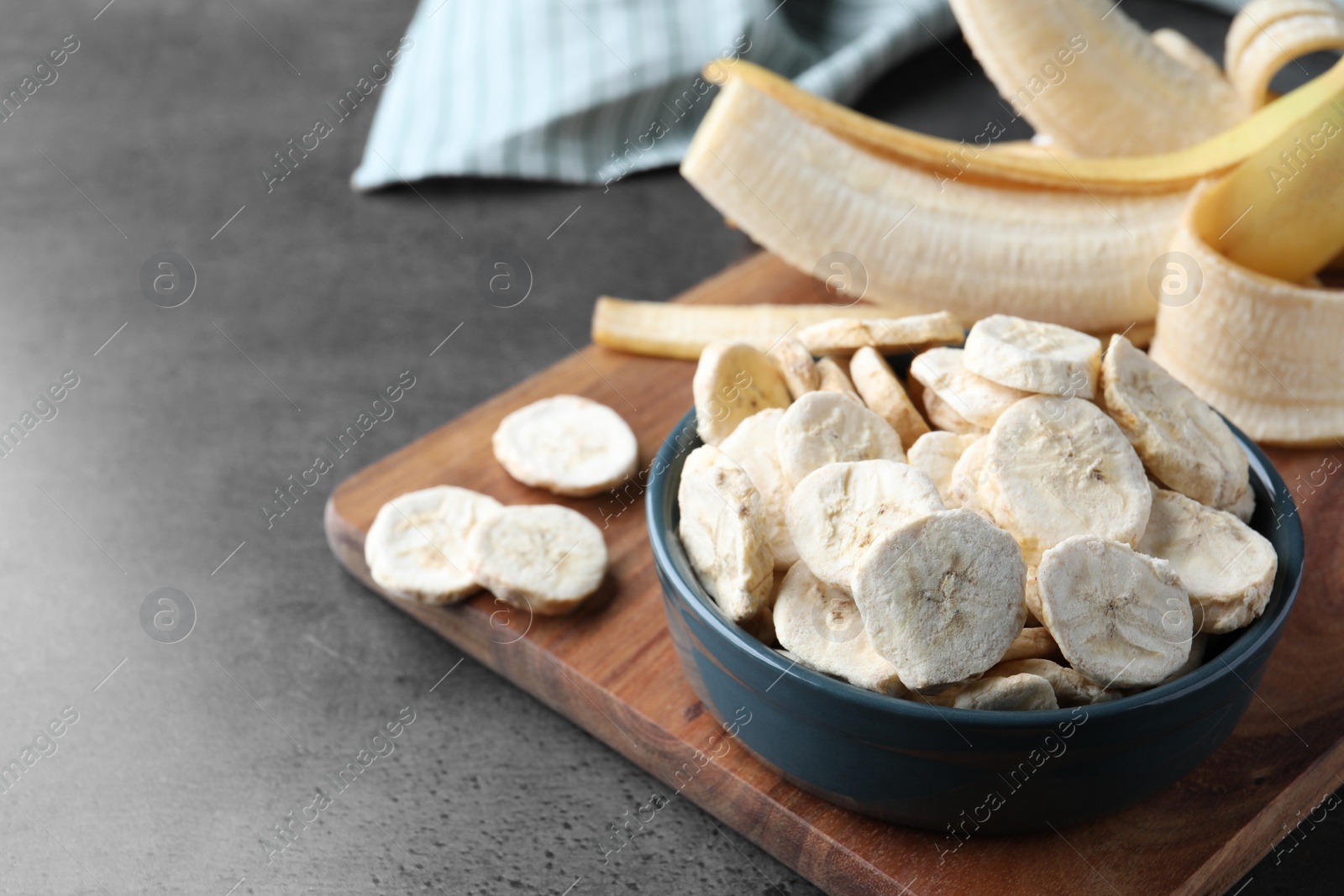 Photo of Freeze dried and fresh bananas on grey table. Space for text