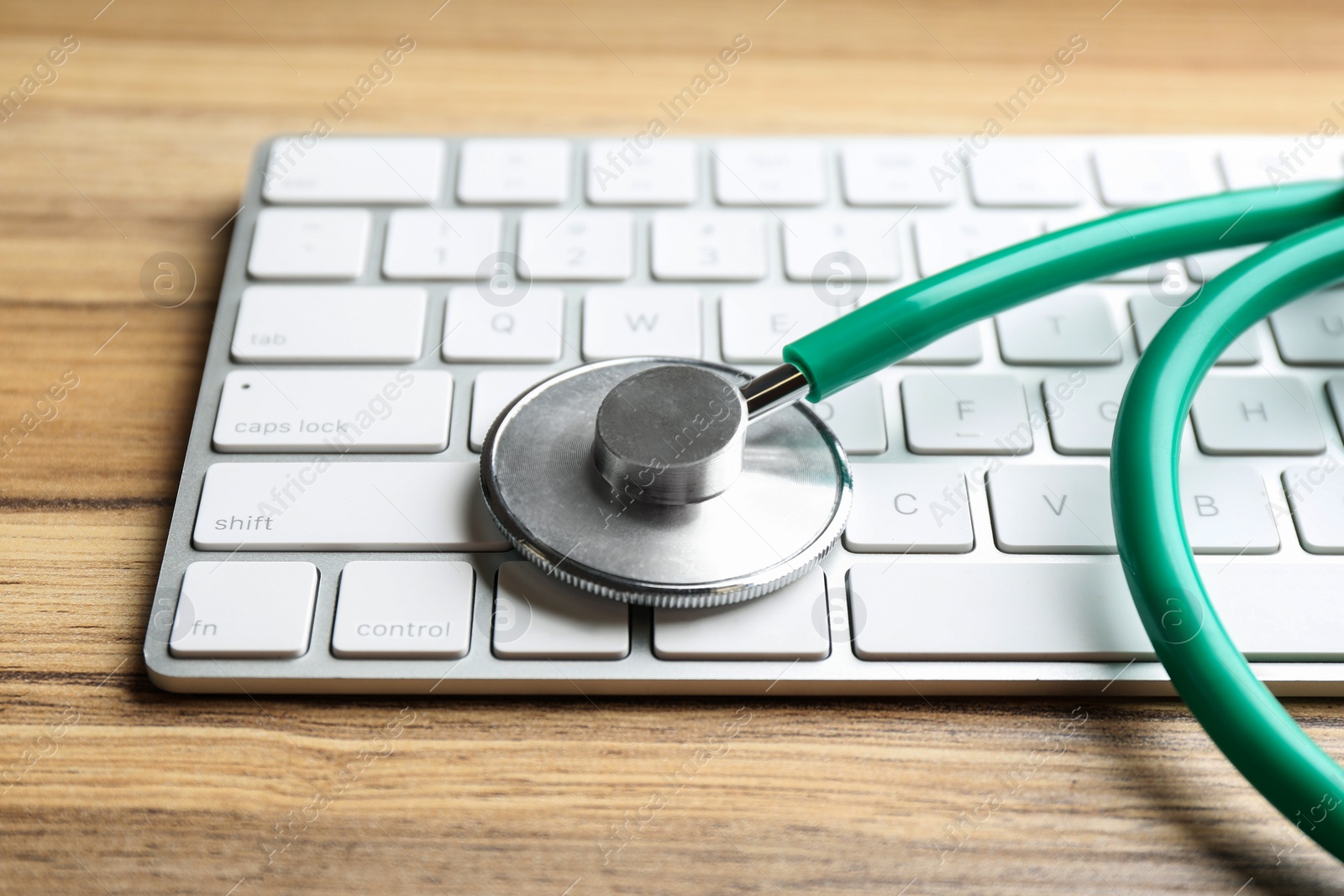 Photo of Keyboard and stethoscope on wooden table, closeup. Concept of technical support