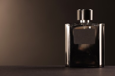 Luxury men`s perfume in bottle on table against dark background, space for text