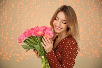 Photo of Portrait of smiling young girl with beautiful tulips on blurred background. International Women's Day