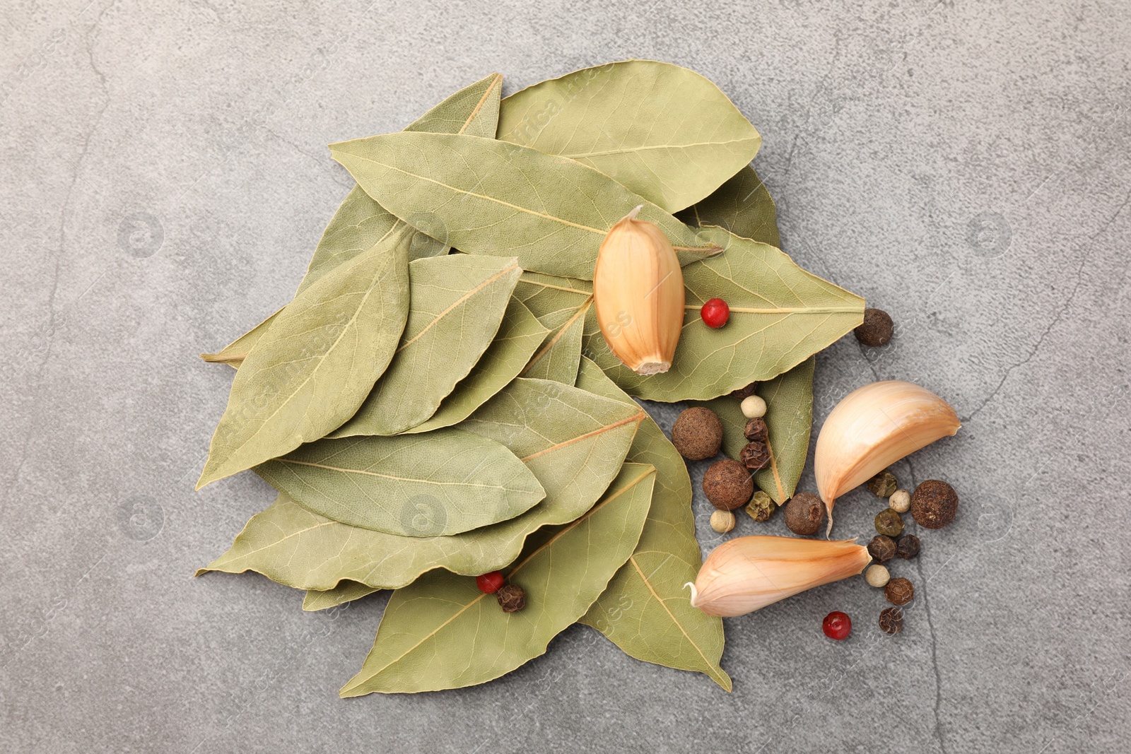 Photo of Aromatic bay leaves and spices on light gray table, flat lay