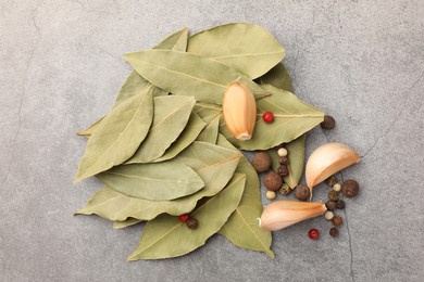 Aromatic bay leaves and spices on light gray table, flat lay