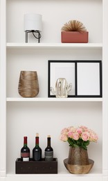 Shelves with different decor and rose flowers indoors. Interior design