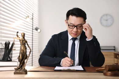 Photo of Notary writing notes at wooden table in office