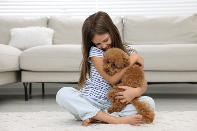 Little child with cute puppy on carpet at home. Lovely pet