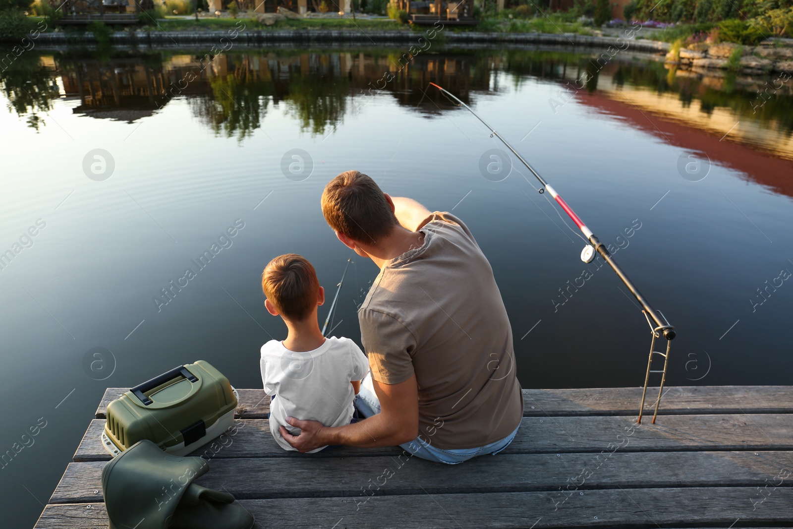 Photo of Dad and son fishing together on sunny day