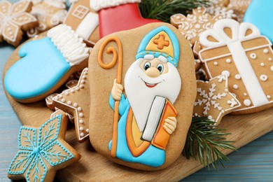 Photo of Tasty gingerbread cookies and fir branches on light blue table, closeup. St. Nicholas Day celebration
