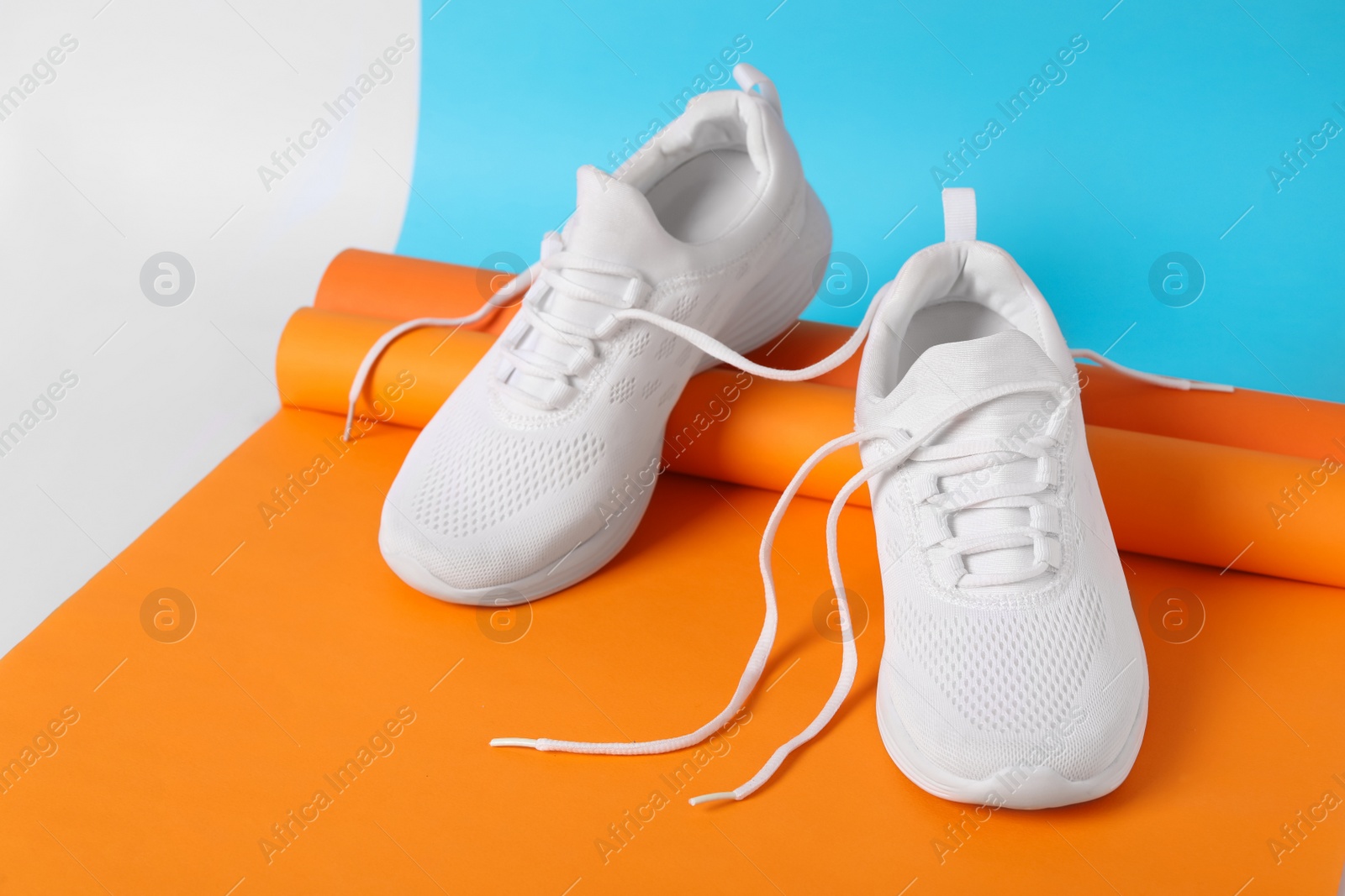 Photo of Stylish sneakers with white shoe laces on color background