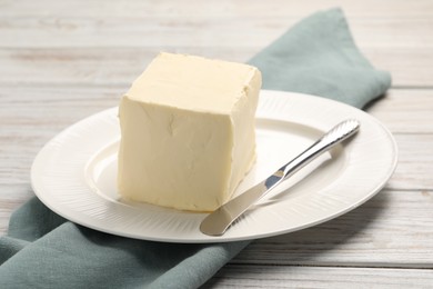 Photo of Block of tasty butter and knife on white wooden table