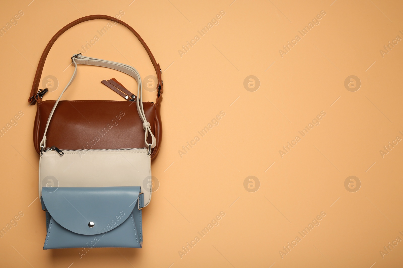 Photo of Different stylish women's bags on pale orange background, flat lay. Space for text