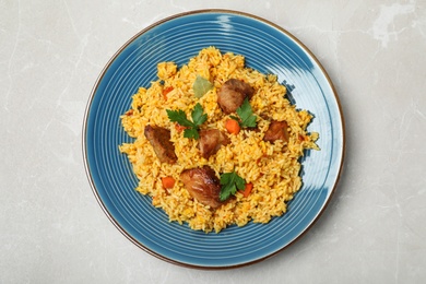 Plate with delicious rice pilaf on light background, top view