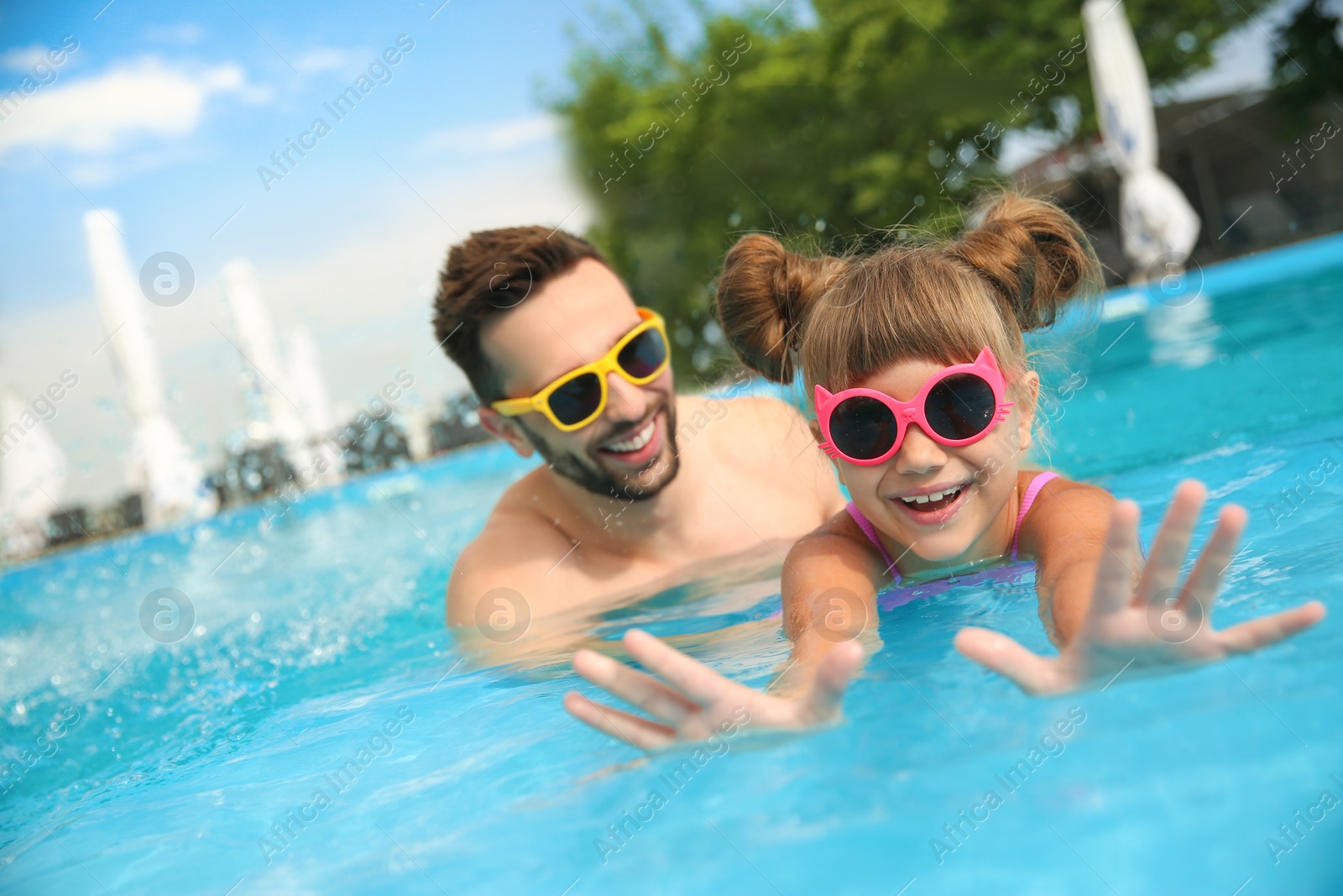 Photo of Father and daughter having fun in swimming pool. Family vacation