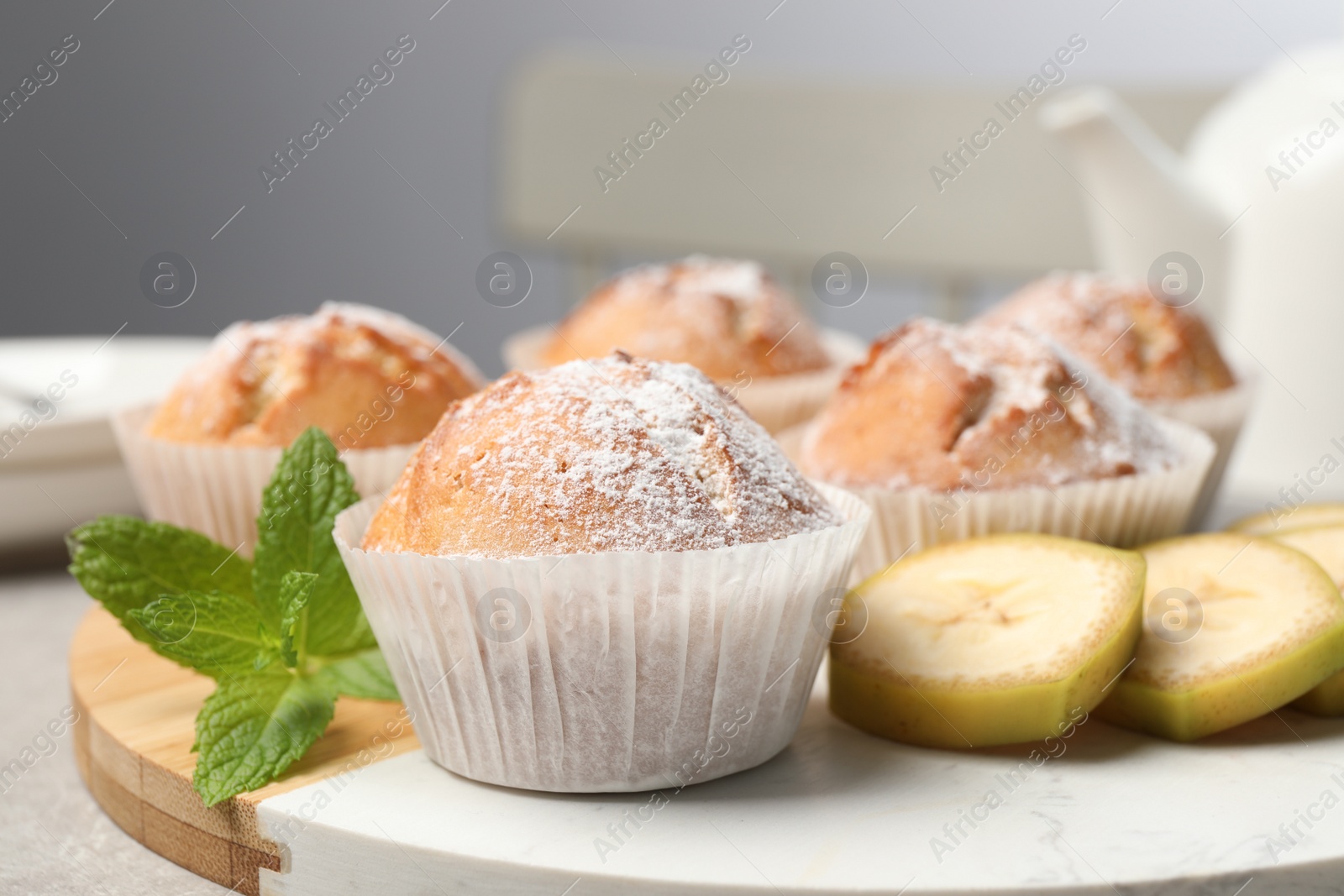 Photo of Tasty muffins served with mint and banana on board, closeup