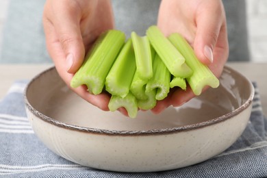 Photo of Woman with fresh cut celery at white table indoors, closeup