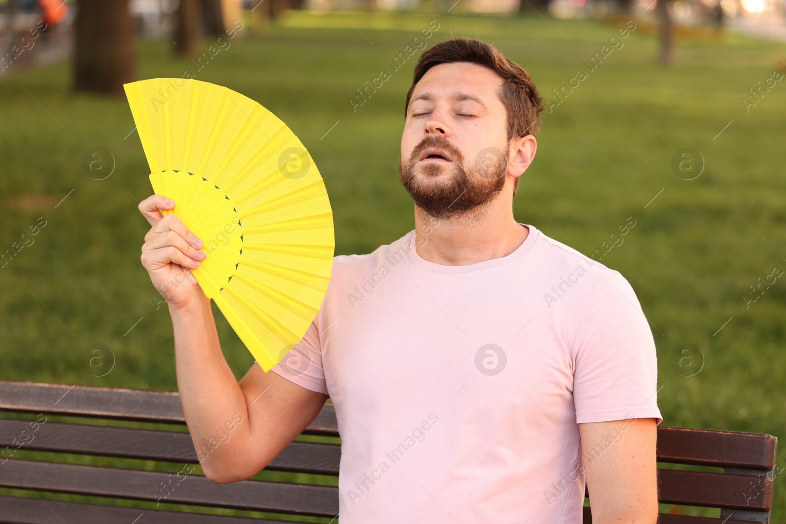 Photo of Man with hand fan suffering from heat outdoors