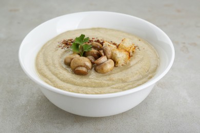 Photo of Delicious cream soup with mushrooms and croutons on beige textured table, closeup