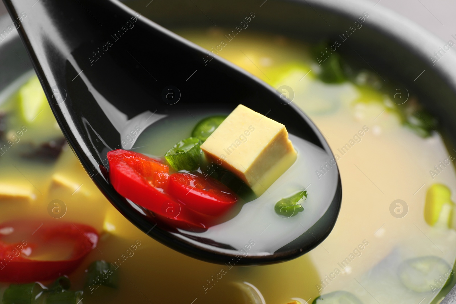 Photo of Eating delicious miso soup with tofu from bowl, closeup