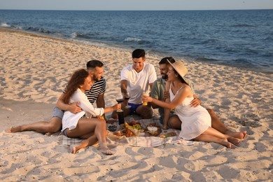 Photo of Group of friends having picnic on sandy beach near sea