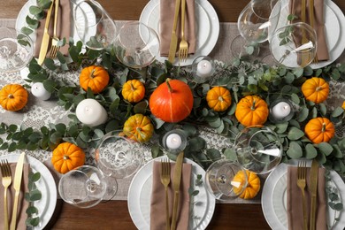 Beautiful autumn table setting. Plates, cutlery, glasses, pumpkins and floral decor, flat lay