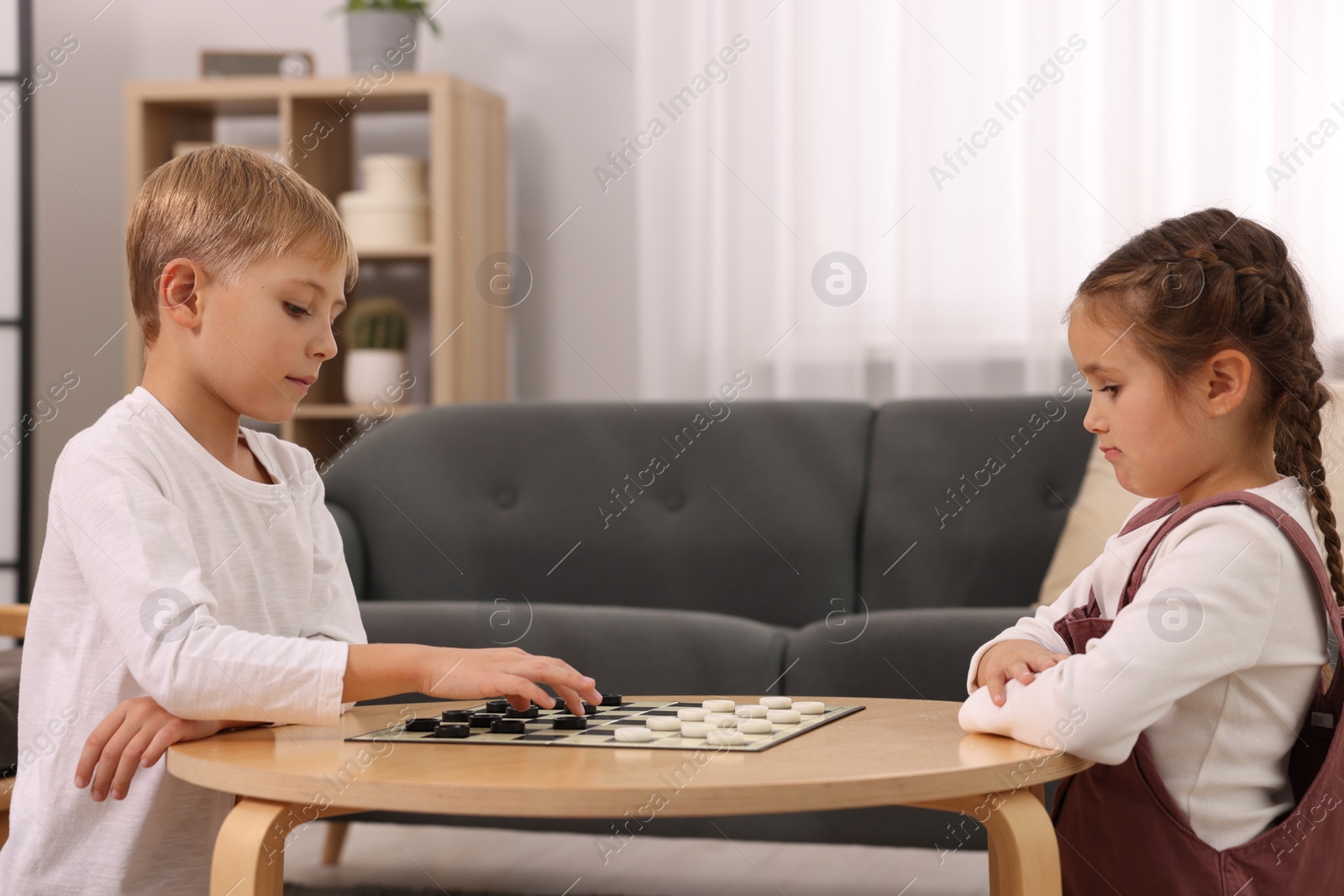 Photo of Children playing checkers at coffee table in room