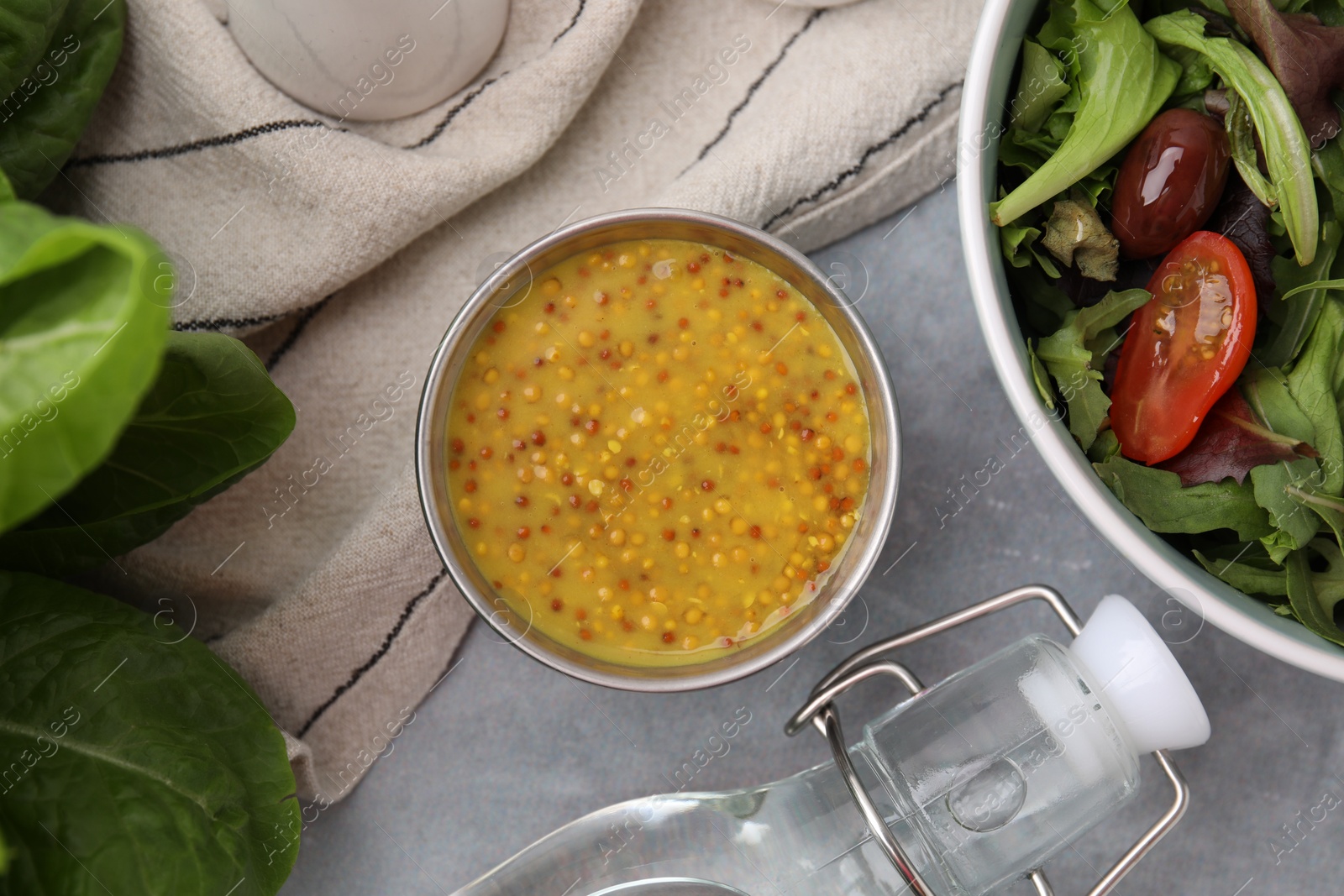 Photo of Tasty vinaigrette in bowl, vinegar and salad on grey table, flat lay