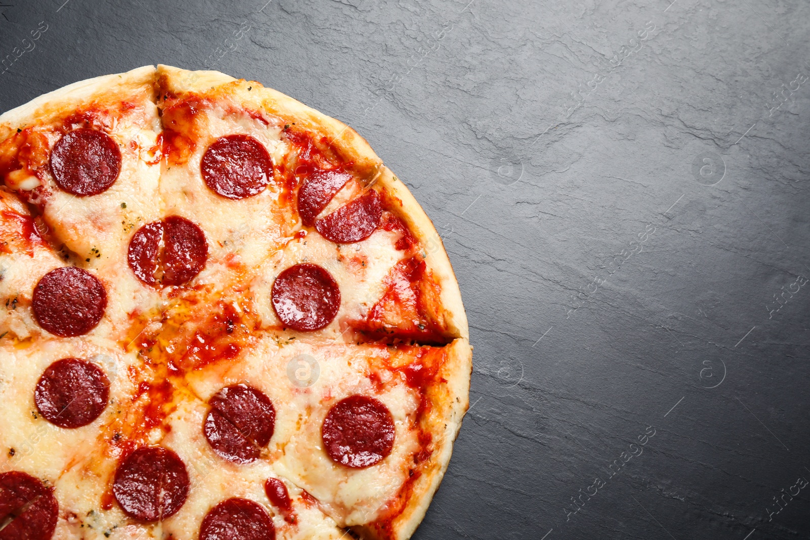 Photo of Hot delicious pepperoni pizza on dark table, top view. Space for text