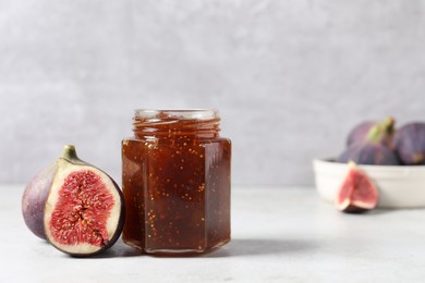 Photo of Jar of tasty sweet jam and fresh figs on white table. Space for text