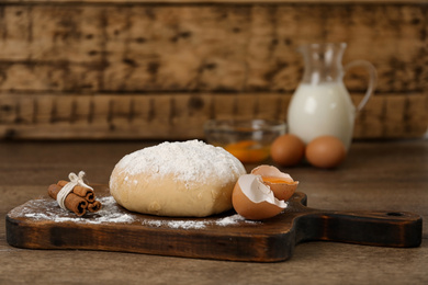Photo of Raw eggs, dough and cinnamon on wooden table. Baking pie