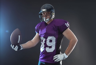 American football player with ball on dark background