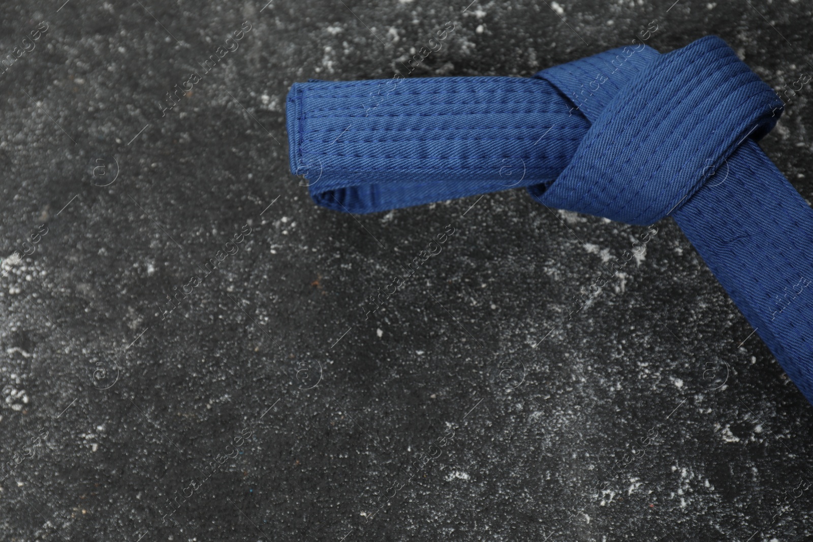 Photo of Blue karate belt on gray textured background, top view. Space for text